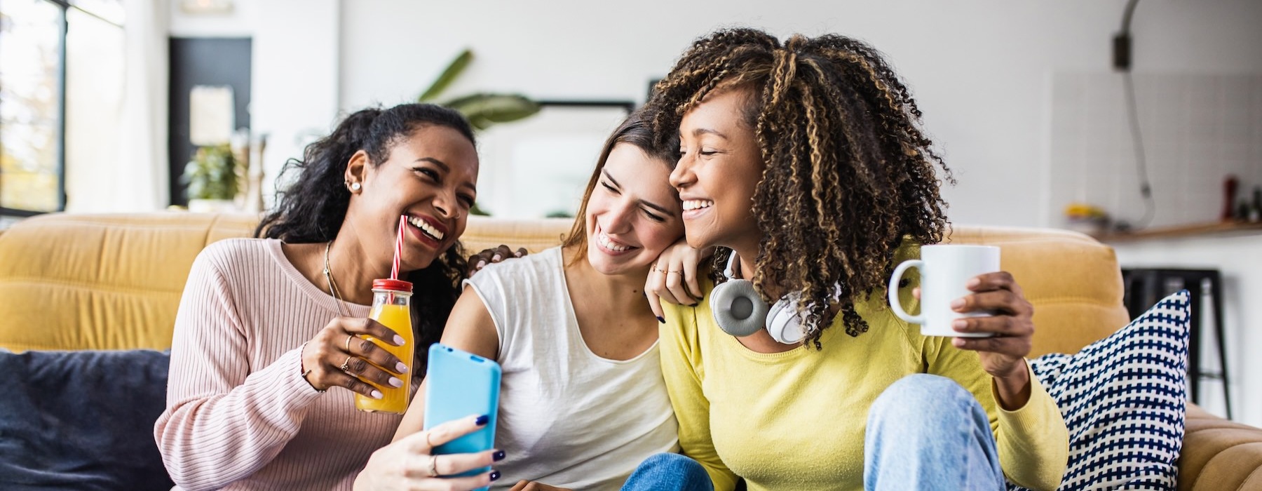 a group of women sitting on a couch looking at a phone