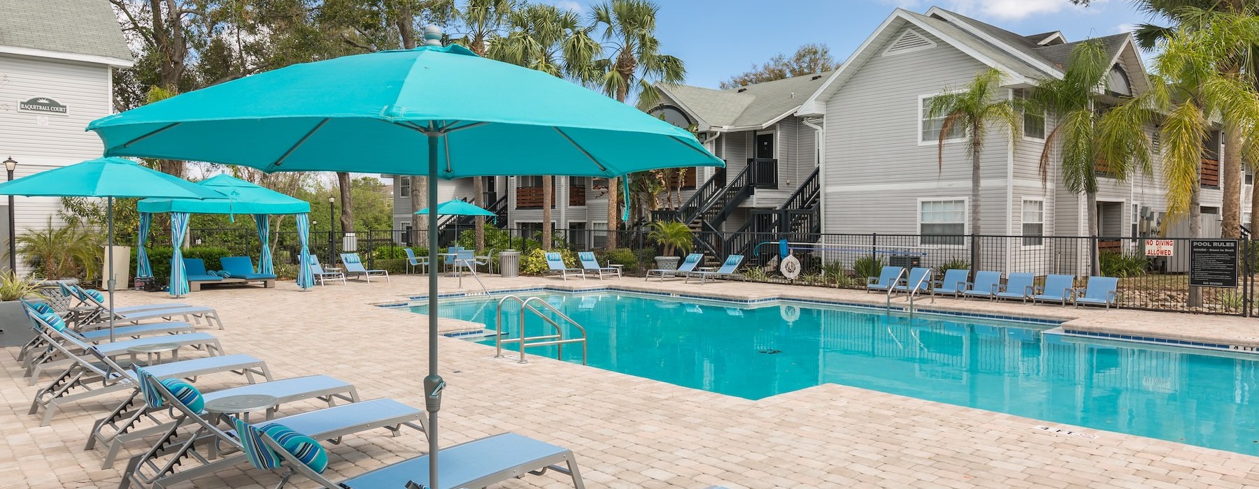 a pool with lounge chairs and umbrellas by it